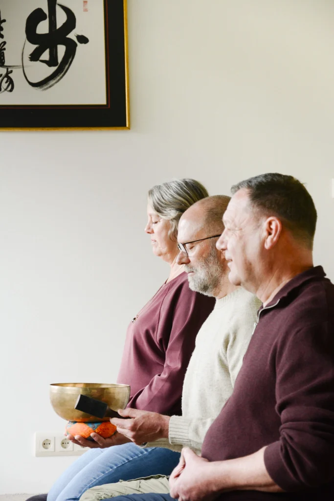 Robert Kizen en twee leden van Zen Brabantse Wal zitten met gesloten ogen in een meditatiepositie.